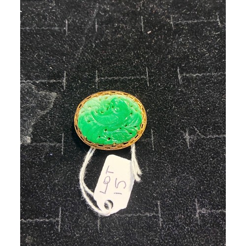 15 - A jadeite and gold brooch, circa 1950The Chinese pierced and carved apple green jadeite depicting a ... 
