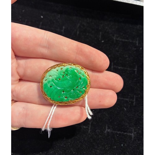 15 - A jadeite and gold brooch, circa 1950The Chinese pierced and carved apple green jadeite depicting a ... 