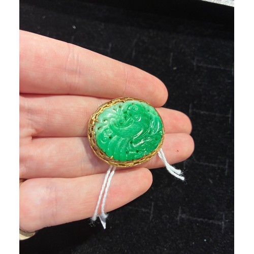 15 - A jadeite and gold brooch, circa 1950The Chinese pierced and carved apple green jadeite depicting a ... 