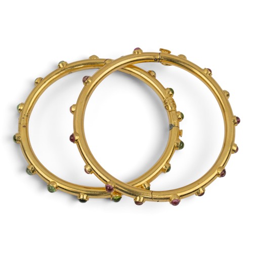 20 - A pair of 18ct gold red and green tourmaline banglesEach hoop set with small circular cabochon colle... 