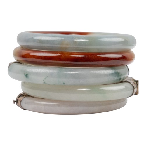 42 - Chinese, A pair of russet and celadon jade bracelets, circa 1950Together with an early 20th century ... 