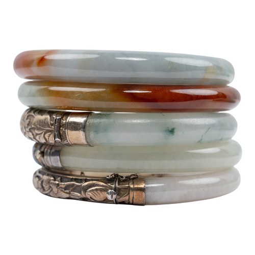 42 - Chinese, A pair of russet and celadon jade bracelets, circa 1950Together with an early 20th century ... 