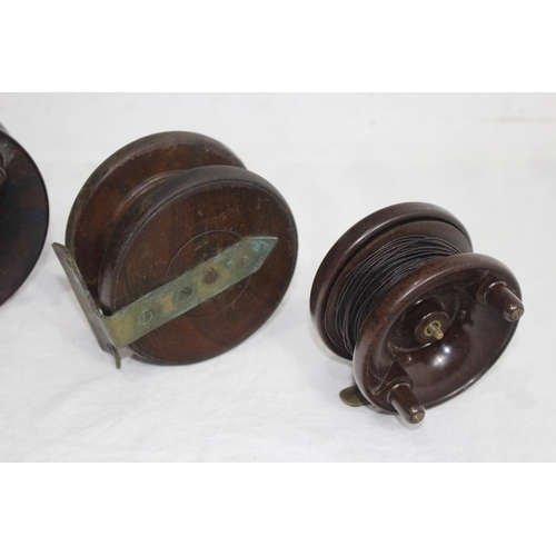 332 - 4 X LARGE FISHING REELS - 3 ARE WOODEN AND 1 IS BAKELITE