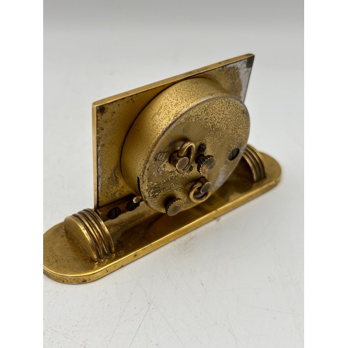 262 - Interesting Little Brass Desk Clock With Birdseye Logo And Dates. Tics When Wound.