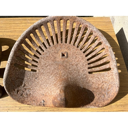 426 - Two cast iron tractor seats. {Largest 93 cm W x 40 cm H}