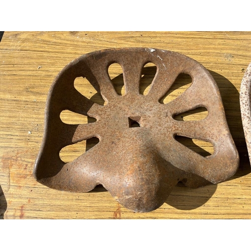 426 - Two cast iron tractor seats. {Largest 93 cm W x 40 cm H}