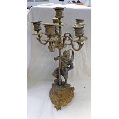 1075 - A CAST METAL CANDLE STICK HOLDER DECORATED WITH A KNIGHT WITH LARGE PLUME TO HELMET ON A HEAVILY DEC... 