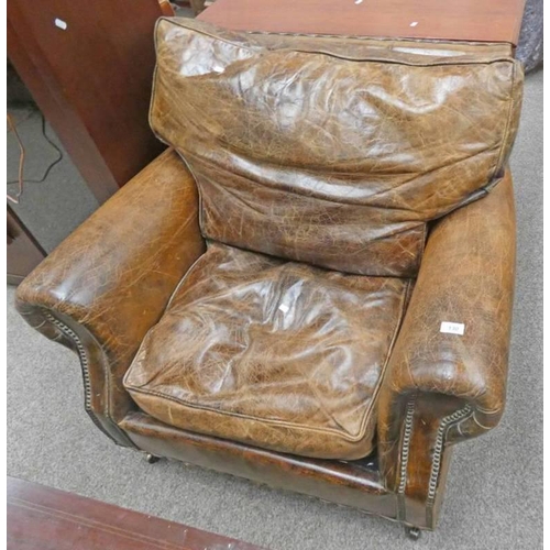 130 - EARLY 20TH CENTURY OVERSTUFFED LEATHER ARMCHAIR ON TURNED SUPPORTS