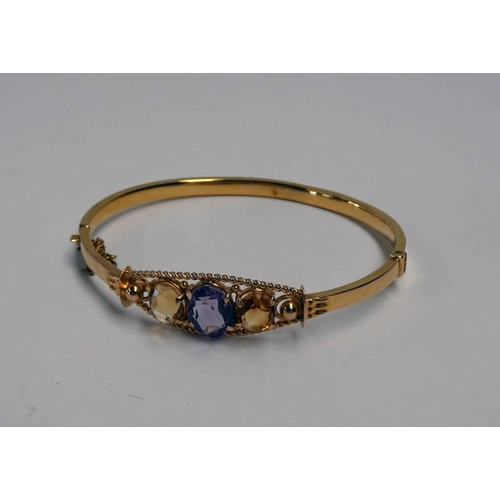 692 - EARLY 20TH CENTURY 9CT GOLD HINGED BANGLE SET WITH AN OVAL AMETHYST FLANKED BY 2 CITRINES WITHIN A R... 