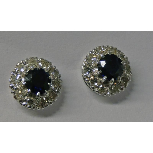 433 - PAIR OF SAPPHIRE & DIAMOND CLUSTER EARSTUDS, THE CIRCULAR CUT SAPPHIRE SET WITHIN A SURROUND OF 10 B... 