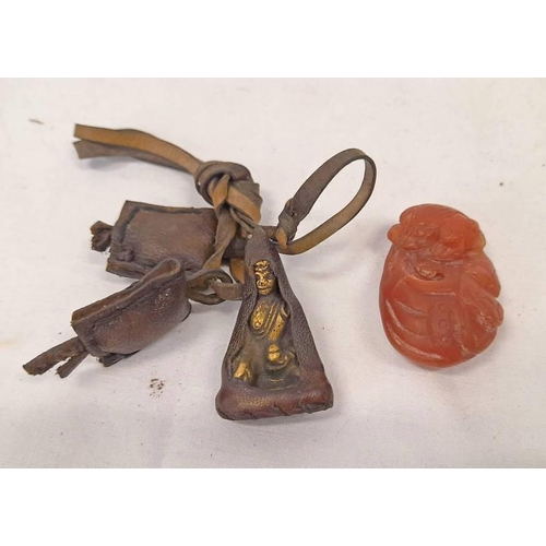 1127 - CARVED CARNELIAN / STONE NETSUKE AND A BRASS RELIGIOUS FIGURE WRAPPED IN LEATHER WITH LEATHER STRAP ... 