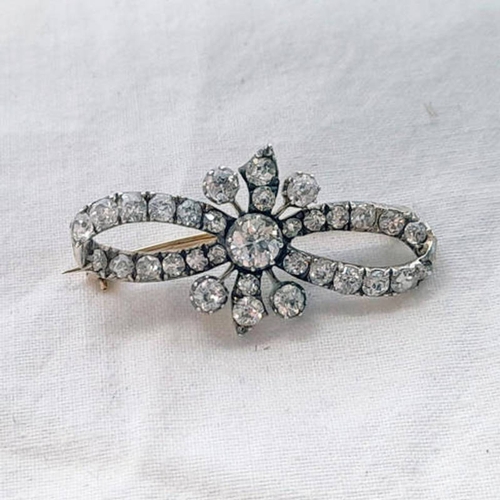 111 - 19TH CENTURY RIBBON BOW DIAMOND SET BROOCH, THE CENTRAL DIAMOND APPROX 0.4 CARATS - 3.6CM LONG