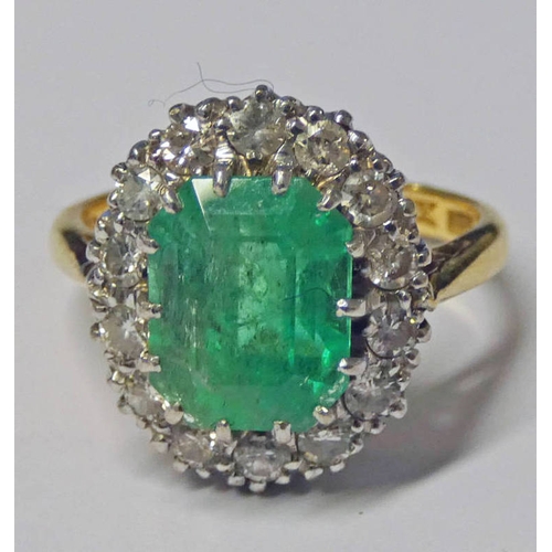 43 - 18CT GOLD EMERALD & DIAMOND CLUSTER RING, THE OCTAGONAL CUT EMERALD SET WITHIN A SURROUND OF 14 BRIL... 