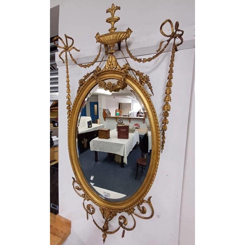 1081 - GILT FRAMED OVAL WALL MIRROR, DECORATED WITH VARIOUS FLORAL & LEAFED ADDITIONS