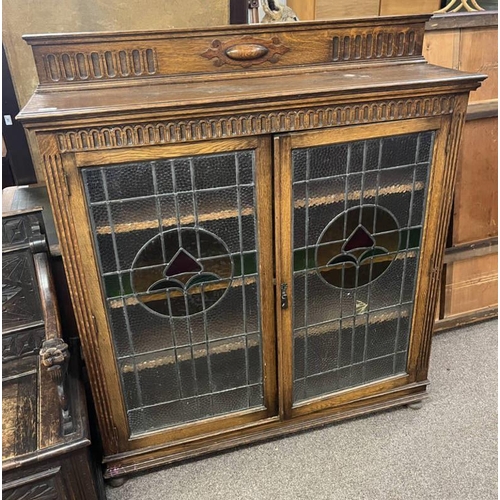 13 - EARLY 20TH CENTURY OAK 2 DOOR BOOKCASE WITH LEADED GLASS PANEL DOORS ON BUN FEET - 140CM TALL