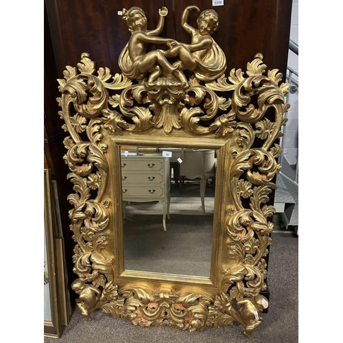 48 - OVERMANTLE MIRROR WITH DECORATIVE CARVED GILT FRAME SURMOUNTED BY 2 CHERUBS, INNER DIMENSIONS 61CM T... 