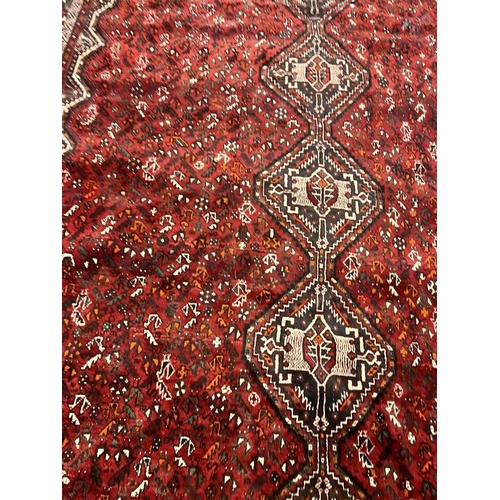 1553 - LARGE RED GROUND MIDDLE EASTERN CARPET BY THE PERSIAN RUG COMPANY, 250 X 360 CM