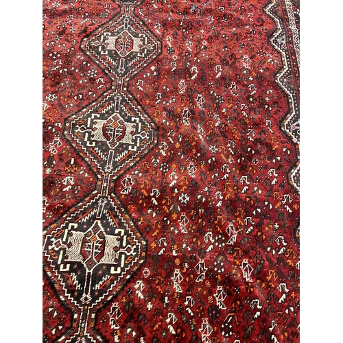 1553 - LARGE RED GROUND MIDDLE EASTERN CARPET BY THE PERSIAN RUG COMPANY, 250 X 360 CM