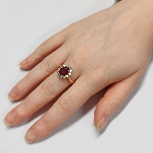 173 - 14K GOLD RUBY & DIAMOND CLUSTER RING THE OVAL RUBY SET WITHIN A SURROUND OF 12 DIAMONDS APPROX 0.6 C... 