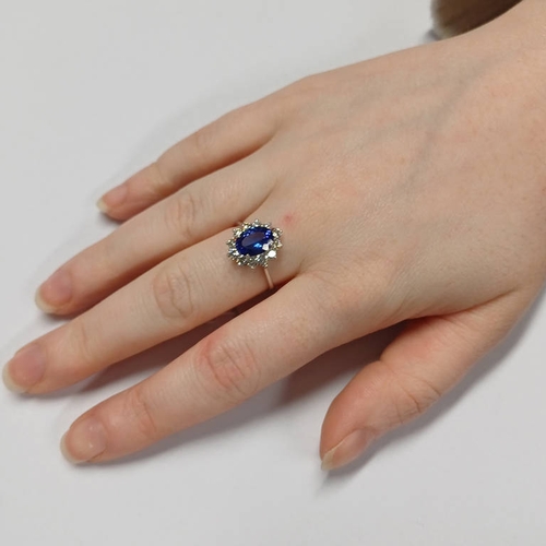 47 - 18 CT GOLD TANZANITE & DIAMOND CLUSTER RING, THE OVAL FACETED TANZANITE SET WITHIN A SURROUND OF 12 ... 