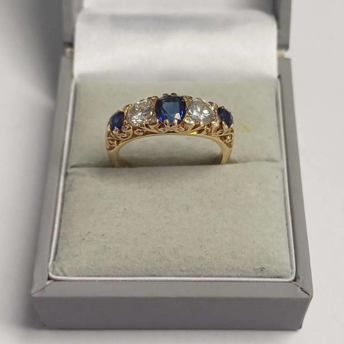 103 - 18CT GOLD SAPPHIRE & DIAMOND 5-STONE RING IN SCROLL SETTING, THE CENTRAL OVAL SAPPHIRE FLANKED BY 2 ... 