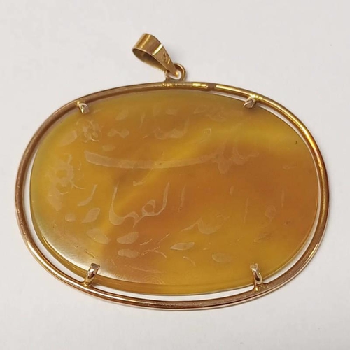 106 - 14K GOLD MOUNTED OVAL HARDSTONE PENDANT INSCRIBED WITH ARABIC SCRIPT - 5.5CM WIDE, 15.8G