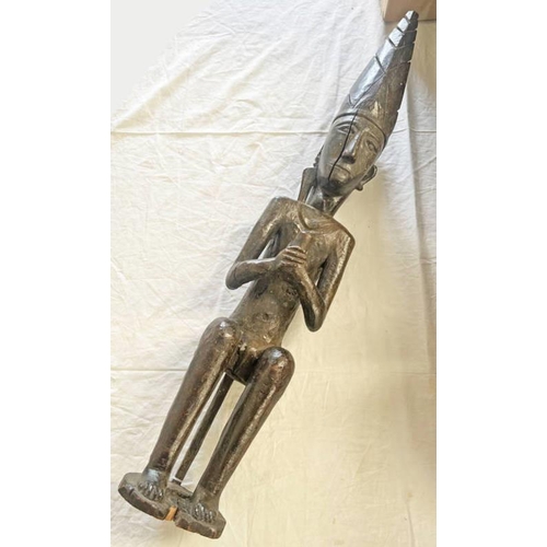 1335 - HARDWOOD AFRICAN FIGURE WITH TALL TRIANGULAR HEAD DRESS HOLDING CHALLIS  84CM TALL