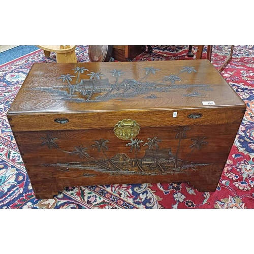 152 - EASTERN CAMPHOR WOOD TRUNK WITH BRASS FIXTURES & CARVED ORIENTAL SCENE DECORATION, 43 CM TALL X 76 C... 