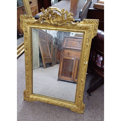 5120 - DECORATIVE GILT FRAMED RECTANGULAR MIRROR SURMOUNTED BY FLORAL DECORATION.  GLASS DIMENSIONS 74 X 49... 