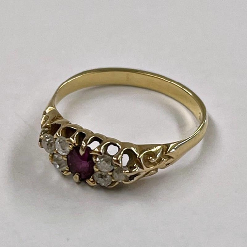 27 - GOLD RUBY  & DIAMOND SET RING IN SCROLL SETTING, THE OVAL RUBY SET WITHIN 2 GROUPS OF 3 CUSHION CUT ... 