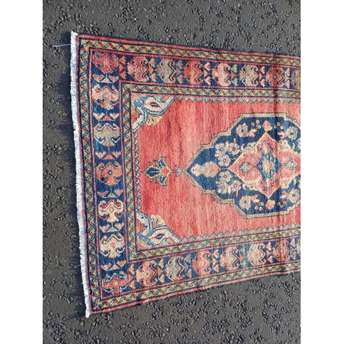 2106 - WASHED RED GROUND AND WOVEN PERSIAN VILLAGE RUG WITH CENTRAL MEDALLION DESIGN 205CM X 125CM