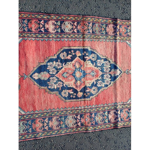 2106 - WASHED RED GROUND AND WOVEN PERSIAN VILLAGE RUG WITH CENTRAL MEDALLION DESIGN 205CM X 125CM