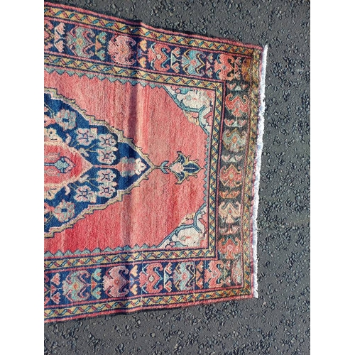 2106 - WASHED RED GROUND AND WOVEN PERSIAN VILLAGE RUG WITH CENTRAL MEDALLION DESIGN 205CM X 125CM