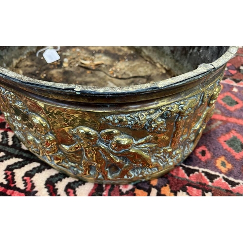 2006 - LATE 19TH OR EARLY 20TH CENTURY BRASS OVAL BIN EMBOSSED WITH CHERUBS IN FOREST SCENE, 49CM ACROSS