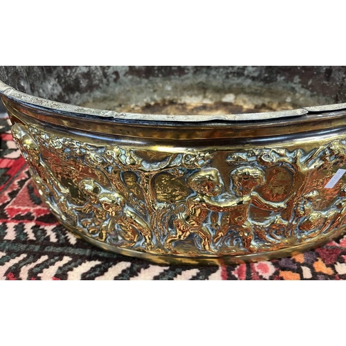 2006 - LATE 19TH OR EARLY 20TH CENTURY BRASS OVAL BIN EMBOSSED WITH CHERUBS IN FOREST SCENE, 49CM ACROSS