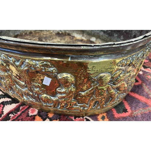 2006 - LATE 19TH OR EARLY 20TH CENTURY BRASS OVAL BIN EMBOSSED WITH CHERUBS IN FOREST SCENE, 49CM ACROSS