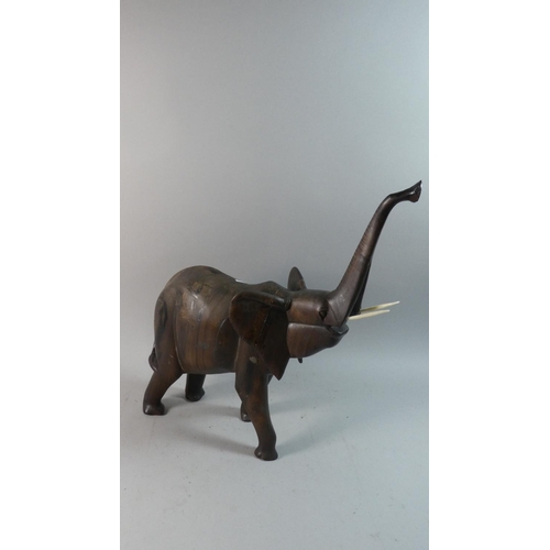 54 - A Carved Wooden Study of an African Elephant with Trunk in Salute, 51cm High