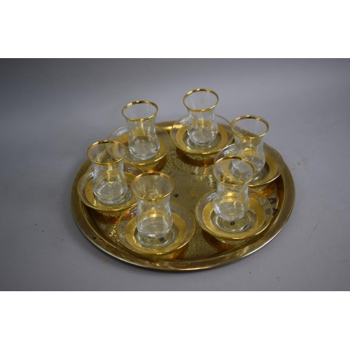 129 - A Circular Brass Islamic Tray together with Six Etched Glasses and Six Moulded Saucers.