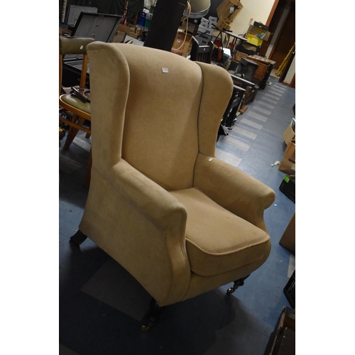 588 - An Upholstered Wing Armchair with Brass Casters
