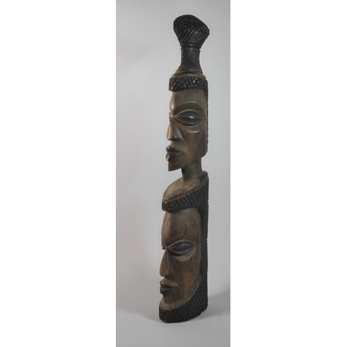 65 - A Heavy Carved Wooden Tribal Club in the Form of Two Graduated Masks, 65cm high