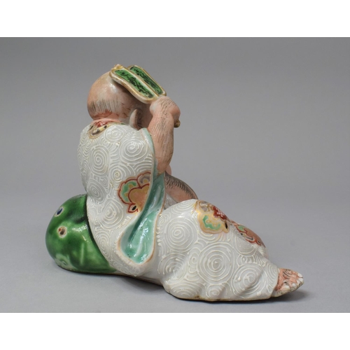 263 - A Japanese Porcelain Figure of Reclining Buddha with Fan, Meiji Period, 13.5cm High