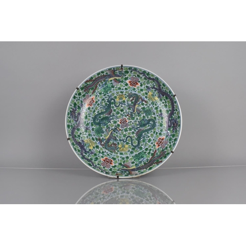 An Impressive Chinese Porcelain Qing Period Charger decorated in the Doucai Palette with Dragons and Phoenix on Foliate Ground, Six Character Mark for Yongzheng within Double Concentric Marks, 37cms Diameter. Condition - running hairline to rim approx 4cm and 1 chip where metal plate brace sits with running hairline approx 7.5cm, unable to tell is brace has caused any other damage. Part of rim appears ground/with wear. We advise viewing