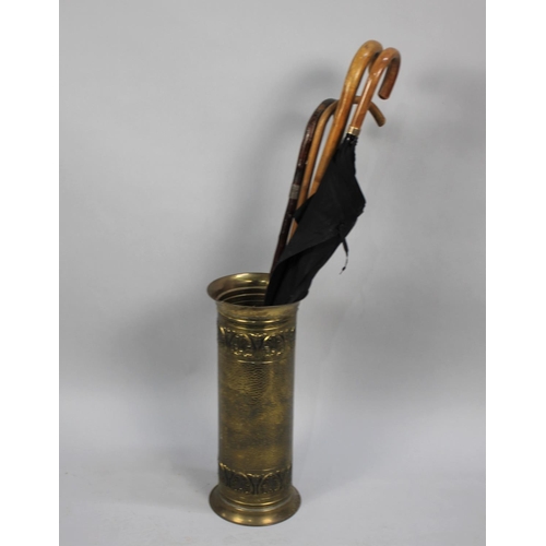 81 - A Pressed Brass Stick Stand containing Three Walking Sticks and an Umbrella