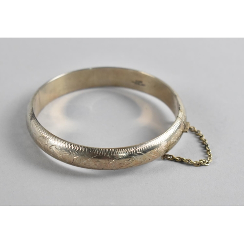 504 - A Sterling Silver Bangle with Safety Chain, Floral Decoration