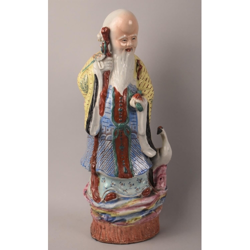 40 - A Large Chinese Glazed Stoneware Figure of Standing Immortal holding Peach Beside Crane, 35cms High