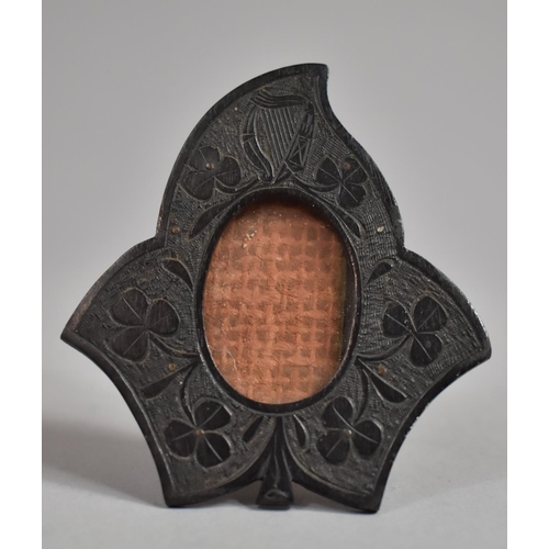 15 - A Small Easel Back Irish Bog Oak Photo Frame in the Form of Leaf with Shamrock and Harp Carved Decor... 