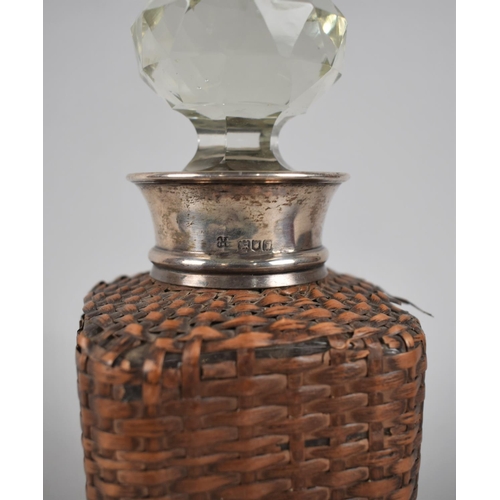 305 - A Glass and Silver Cuffed Decanter with Wicker Case, 23cm high