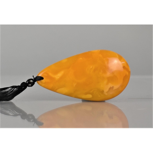 234 - A Large Egg Yolk Amber Pendant on Black Silk Ribbon, Possibly 19th Century, Pear Shaped Pendant Meas... 