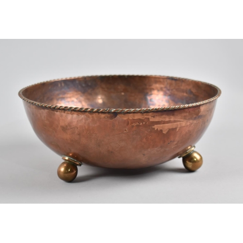 22 - An Arts and Crafts Hammered Copper Bowl, C.1915, Raised on Three Ball Feet with Rope Work Rim. Desig... 