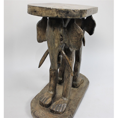 77 - An African Carved Wooden Souvenir Stool, the Supports in the Form of Elephant with Human Legs, Oval ... 